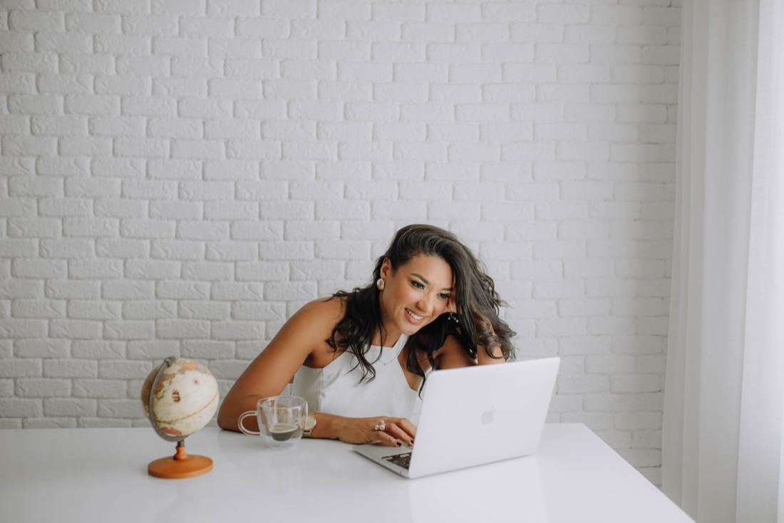 Dalvana Lopes na mesa, com o laptop e um globo